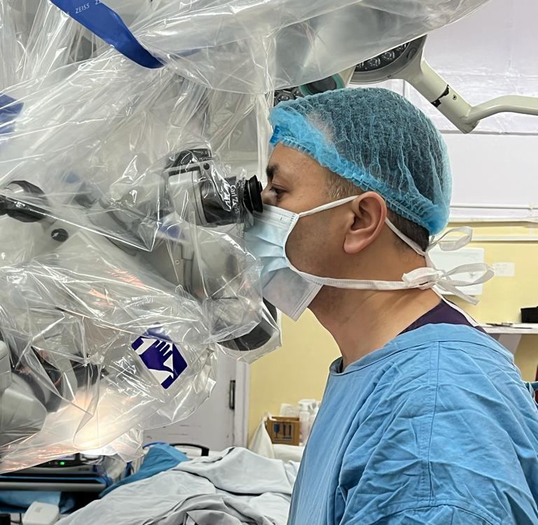 Dr. Somesh Thakur operating under a surgical microscope
